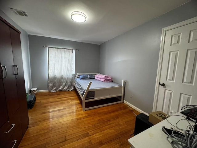 bedroom with hardwood / wood-style floors, baseboards, and visible vents