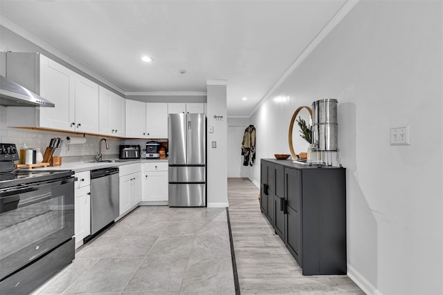 kitchen with ornamental molding, decorative backsplash, appliances with stainless steel finishes, white cabinetry, and a sink