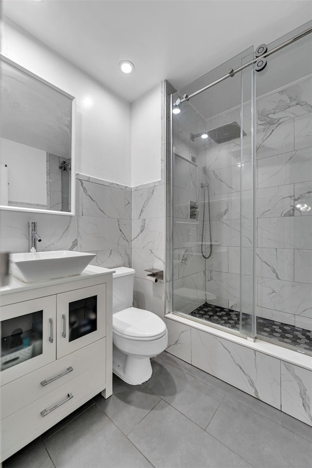 full bath featuring a marble finish shower, toilet, tile walls, and vanity