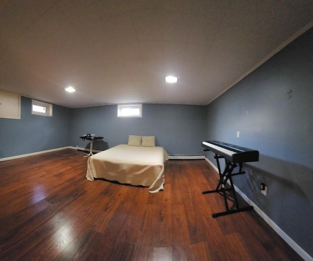 bedroom with a baseboard heating unit, wood finished floors, and baseboards