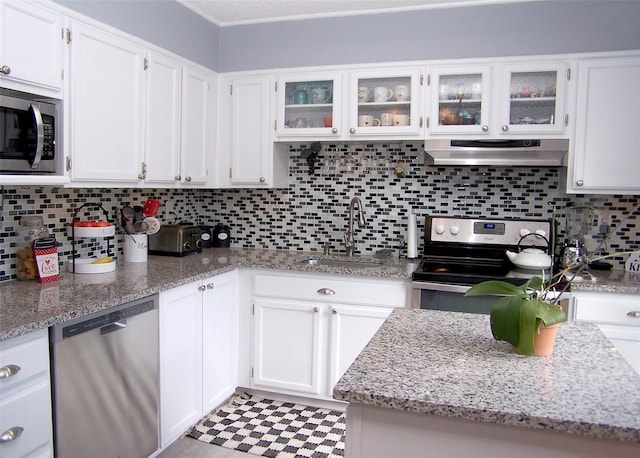 kitchen with range hood, appliances with stainless steel finishes, white cabinetry, and a sink