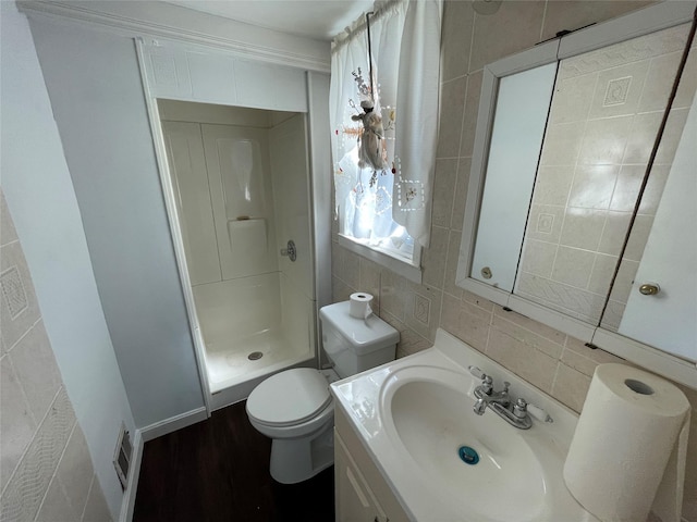 full bathroom with a shower stall, wood finished floors, vanity, tile walls, and toilet