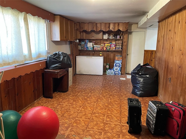 kitchen featuring refrigerator, open shelves, and wooden walls