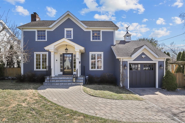 view of front of house with decorative driveway, fence, a shingled roof, a garage, and a chimney