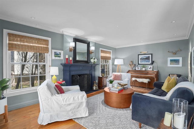 living area with ornamental molding, a brick fireplace, baseboards, and wood finished floors