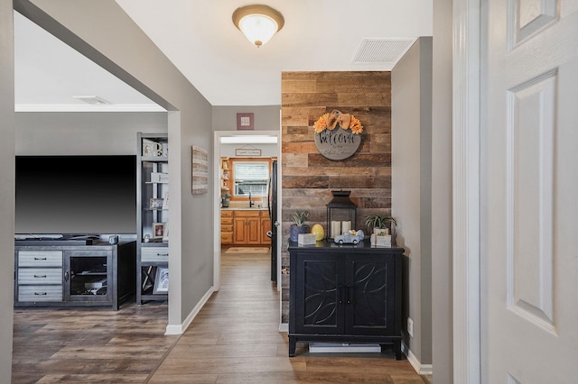 hallway with baseboards, wood finished floors, visible vents, and a sink