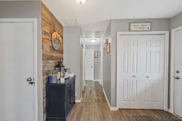 hallway featuring visible vents, baseboards, and wood finished floors