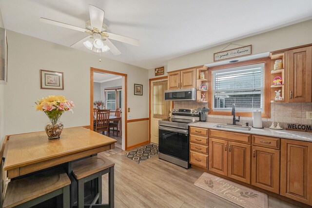 kitchen featuring light wood-style flooring, a sink, open shelves, backsplash, and appliances with stainless steel finishes