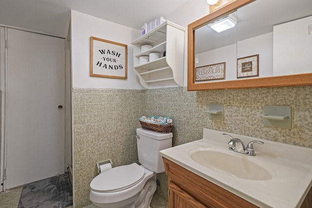 bathroom featuring toilet, tile walls, and vanity