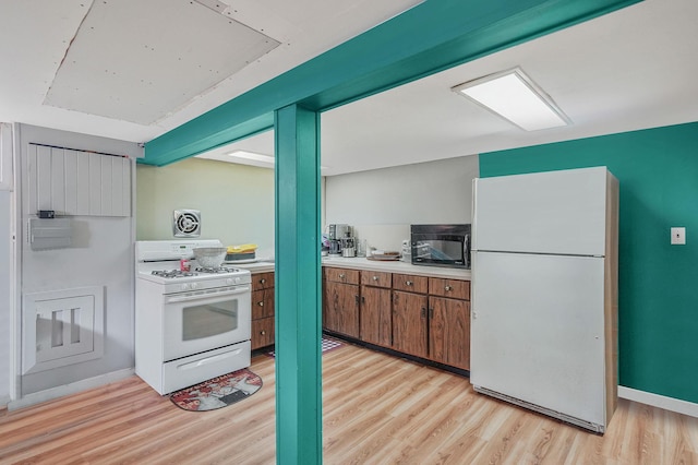 kitchen featuring white appliances, brown cabinetry, baseboards, light countertops, and light wood-type flooring