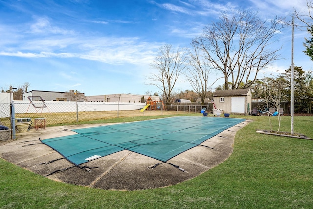 view of swimming pool featuring a storage unit, a lawn, a fenced backyard, an outdoor structure, and a fenced in pool