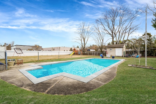 view of pool featuring a playground, a lawn, a fenced backyard, an outdoor structure, and a storage unit