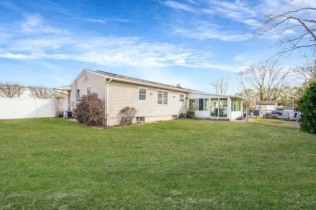 back of house with central AC unit, a lawn, fence, and a sunroom