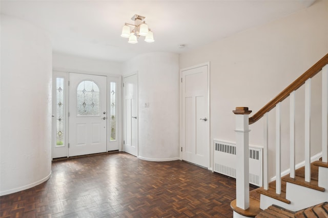 foyer featuring a chandelier, stairway, radiator heating unit, and baseboards