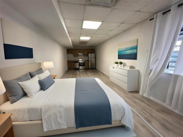 bedroom featuring visible vents, baseboards, light wood-style flooring, freestanding refrigerator, and a paneled ceiling