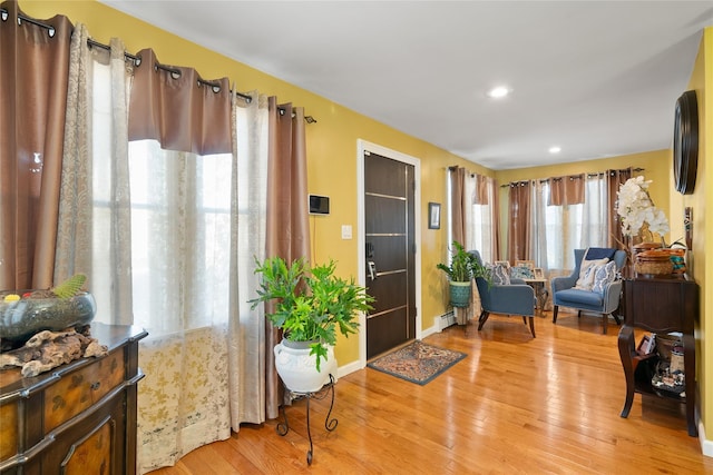 living area featuring recessed lighting, light wood-style flooring, baseboard heating, and baseboards