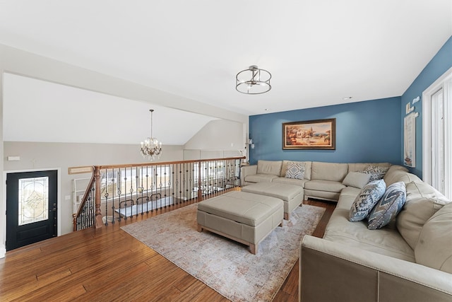 living room with vaulted ceiling, an inviting chandelier, and wood finished floors