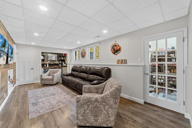 living area featuring recessed lighting, wood finished floors, baseboards, and a drop ceiling