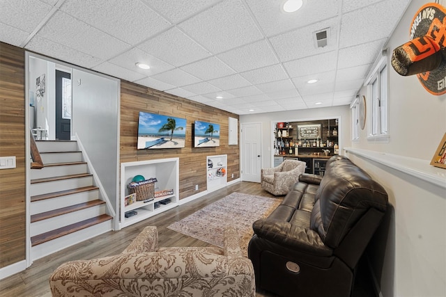 living room with stairway, wood finished floors, visible vents, recessed lighting, and wood walls