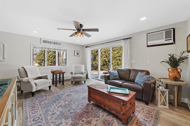 living area featuring a baseboard heating unit, ceiling fan, an AC wall unit, recessed lighting, and light wood-style floors