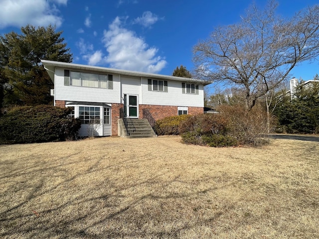 raised ranch with brick siding, a front lawn, and entry steps