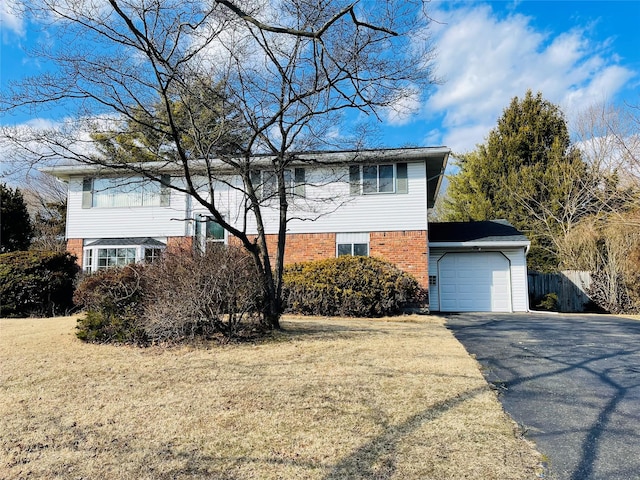 traditional-style home featuring aphalt driveway, brick siding, a front lawn, and fence