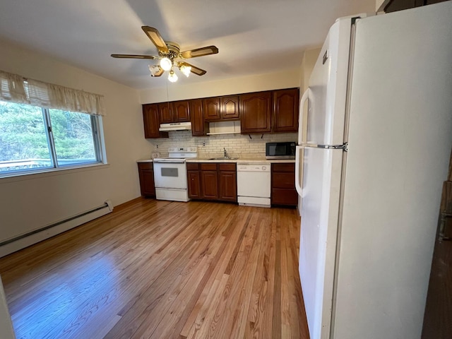 kitchen with under cabinet range hood, a sink, backsplash, white appliances, and light countertops