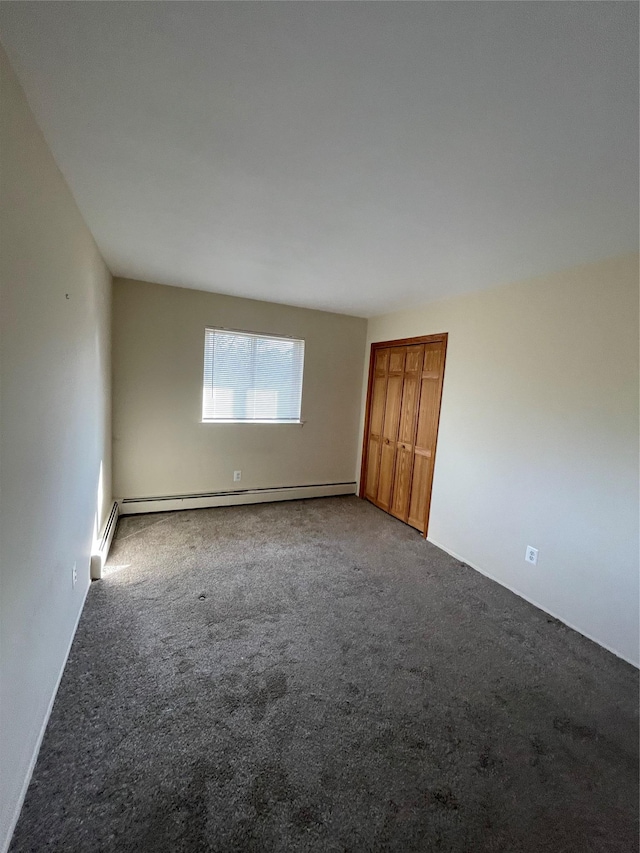 unfurnished room featuring a baseboard heating unit and carpet floors