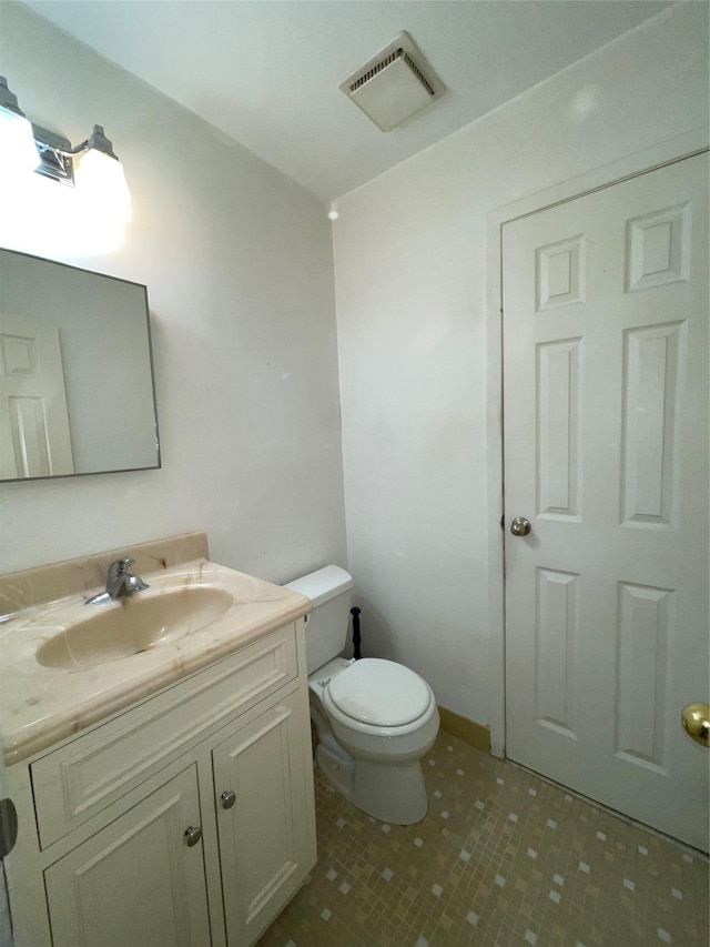 half bathroom with vanity, toilet, and visible vents