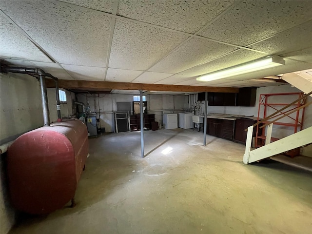 unfinished basement with heating fuel, a paneled ceiling, and independent washer and dryer