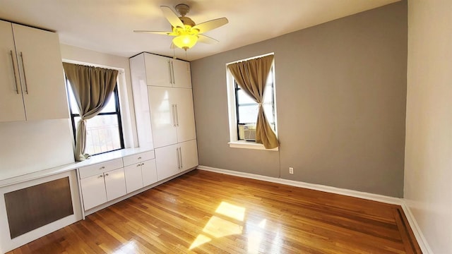 interior space with a ceiling fan, baseboards, and light wood-type flooring