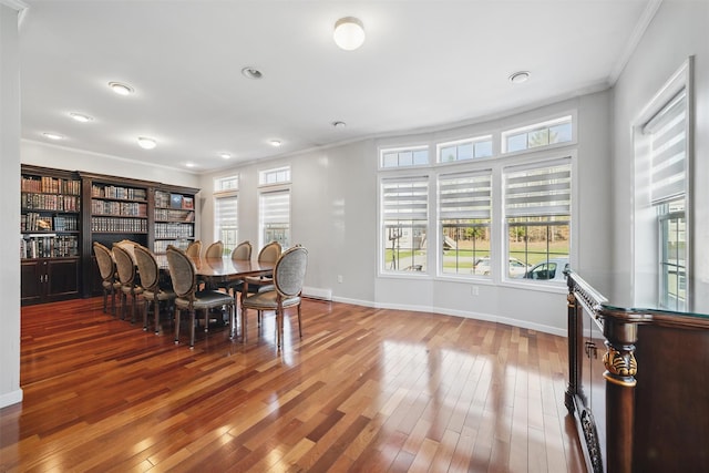 dining room featuring crown molding, baseboards, a healthy amount of sunlight, and wood-type flooring