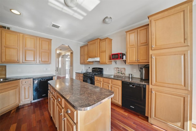 kitchen with dark wood-style flooring, a sink, under cabinet range hood, visible vents, and black appliances