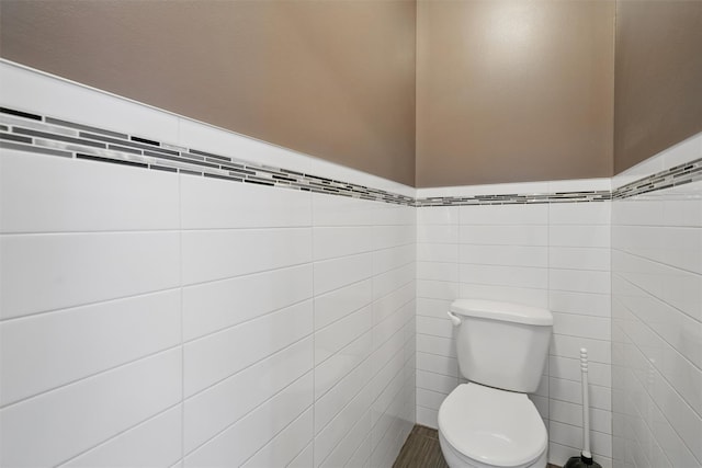 bathroom featuring tile walls and toilet