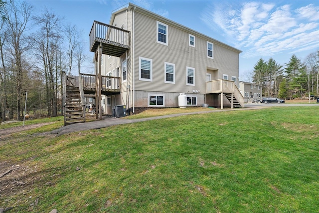 rear view of property with stairway, a lawn, a balcony, and central air condition unit