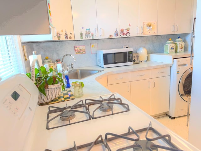 kitchen with light countertops, washer / clothes dryer, backsplash, and a sink