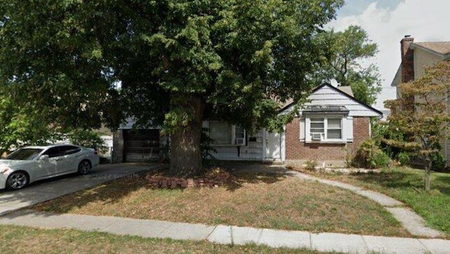 obstructed view of property with a front lawn, an attached garage, brick siding, and driveway