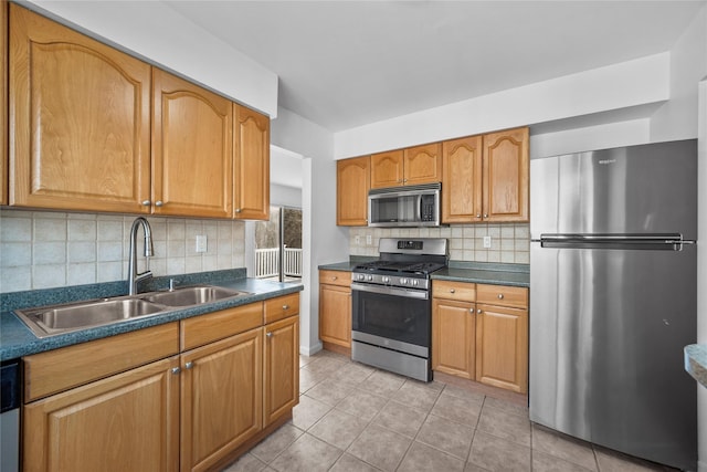 kitchen featuring dark countertops, light tile patterned flooring, stainless steel appliances, and a sink