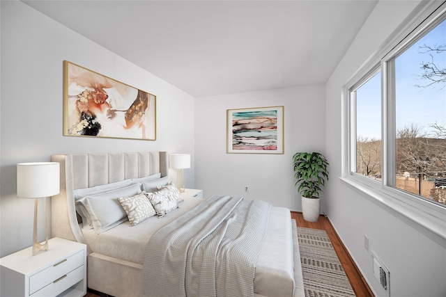 bedroom with wood finished floors, visible vents, and baseboards