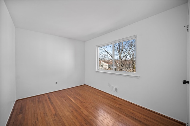 empty room with hardwood / wood-style floors and visible vents