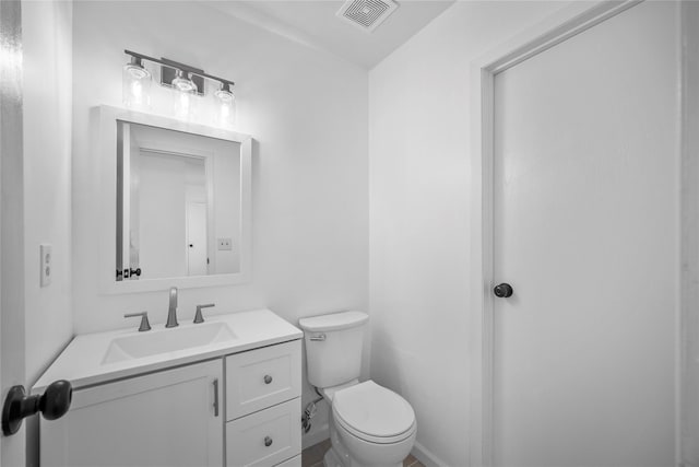 half bath featuring visible vents, toilet, and vanity