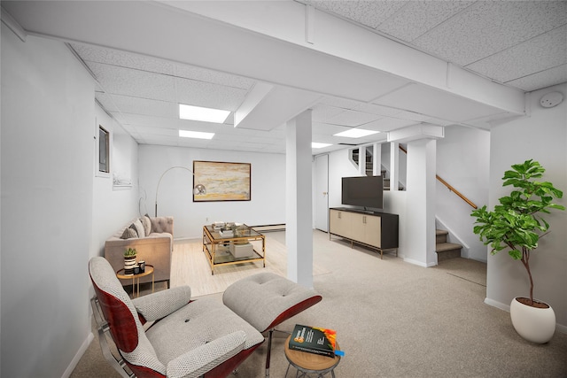 living room with stairway, a paneled ceiling, light colored carpet, and baseboards