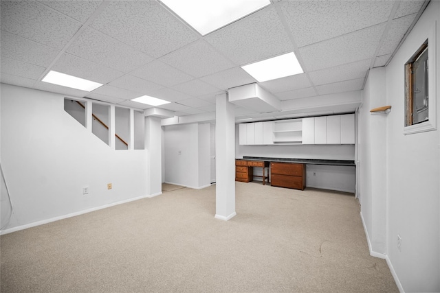 finished basement with stairway, baseboards, a drop ceiling, and light carpet