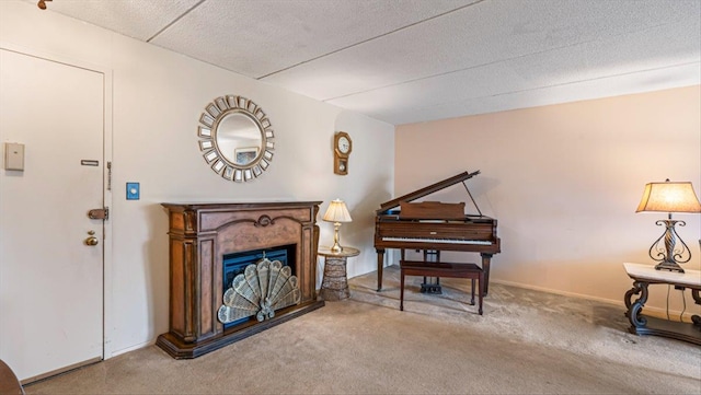 living area featuring a glass covered fireplace, carpet, baseboards, and a textured ceiling