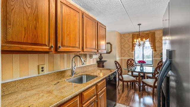 kitchen with wallpapered walls, freestanding refrigerator, a sink, dishwasher, and brown cabinets