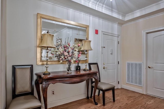 entrance foyer with wood finished floors, visible vents, and ornamental molding