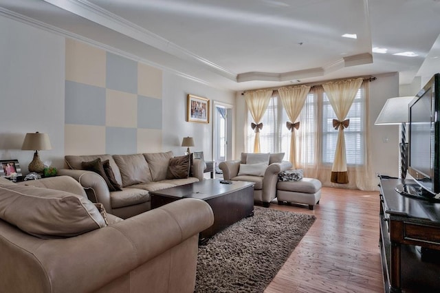 living room featuring a tray ceiling, light wood-style flooring, and crown molding