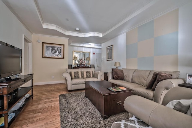 living area with baseboards, crown molding, a tray ceiling, and wood finished floors