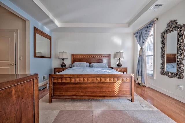 bedroom featuring visible vents, a raised ceiling, and baseboards