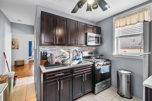 kitchen with a sink, decorative backsplash, ceiling fan, light countertops, and stainless steel appliances